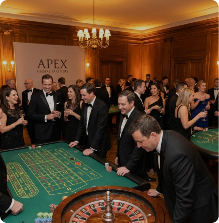 Classic casino atmosphere: guests in tuxedos at roulette and blackjack tables, elegant lighting